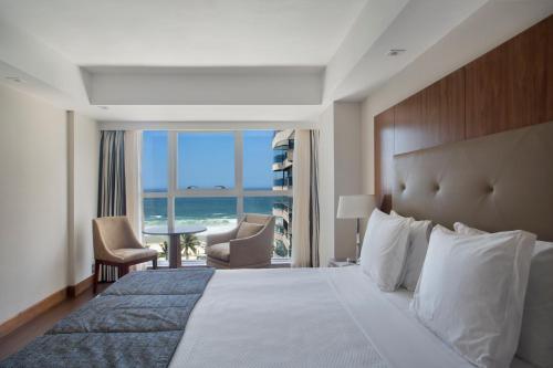 a hotel room with a bed and a view of the ocean at Windsor Marapendi Hotel in Rio de Janeiro