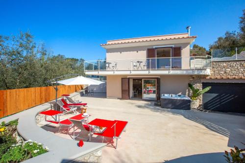 a house with red chairs and a patio at Villa Hemera - Mediterranean elegance with private jacuzzi and Capri views in Massa Lubrense