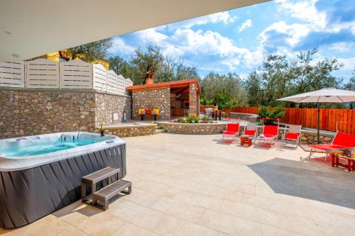 a patio with a hot tub and a table and chairs at Villa Hemera - Mediterranean elegance with private jacuzzi and Capri views in Massa Lubrense