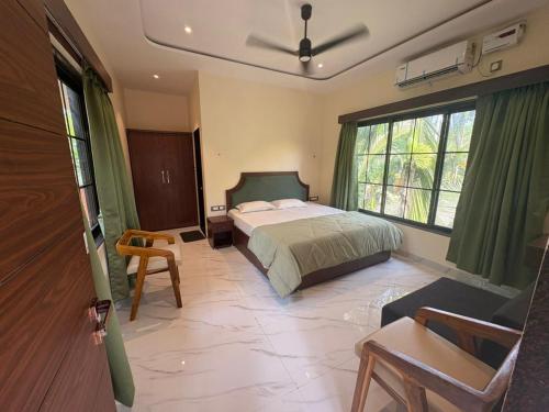 a bedroom with a bed and a chair and a window at Seven Seas Beach Resort in Diveagar