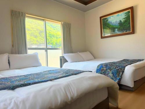 a hotel room with two beds and a window at オリーブママのヤド 凪 バーベキュー機材レンタル可 in Shodoshima