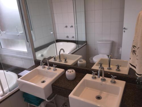 a bathroom with two sinks and a bath tub at Flat 3 suites frente mar in Florianópolis