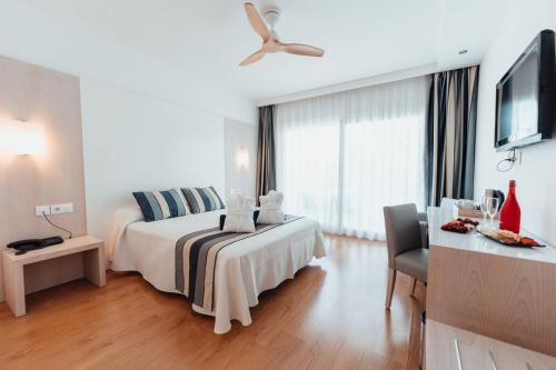 a bedroom with a bed and a table and a tv at Sagitario Playa in Cala Blanca