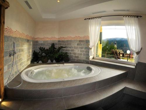 baño con bañera grande y ventana en Hotel Villa Wilma en Folgaria