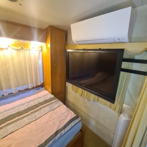 a small bedroom with a large flat screen tv at Quiet caravan in nature on Mur cycle path in Feldkirchen bei Graz