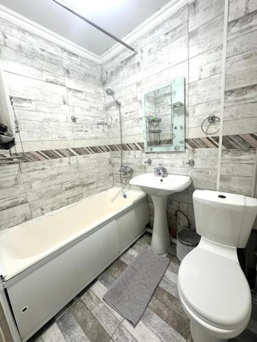 a bathroom with a tub and a toilet and a sink at Apartment Plaza tower in Shymkent