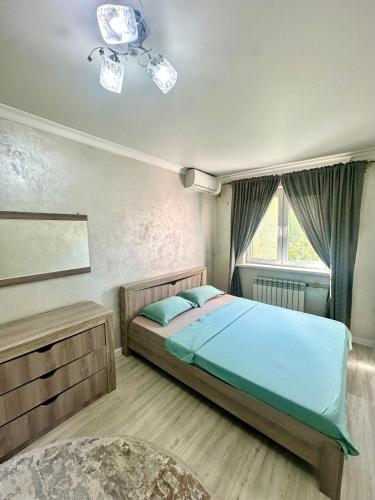 a bedroom with a bed and a window at Apartment Plaza tower in Shymkent