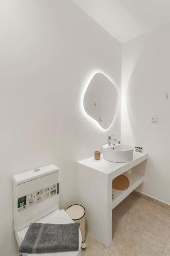 a white bathroom with a sink and a mirror at LausAndros Suites in Andros