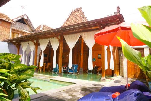 a house with a swimming pool and an umbrella at Villa Joglo Kawung - City Centre Paradise with Pool in Yogyakarta