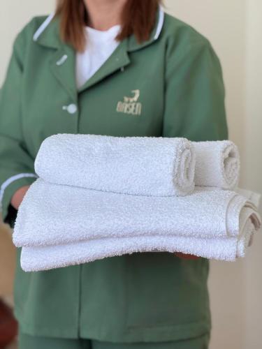 a woman is holding a stack of towels at Hotel Basen in Sisian