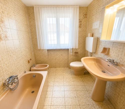 a bathroom with a tub and a toilet and a sink at Residence Caorle Apartments - Agenzia Cocal in Caorle