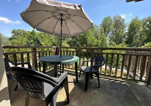 a table and chairs and an umbrella on a balcony at Le Green in Levernois