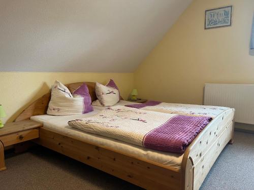 a bedroom with a wooden bed with purple pillows at Gästezimmer Rittergut Inh. Christian Eickhoff in Heldburg