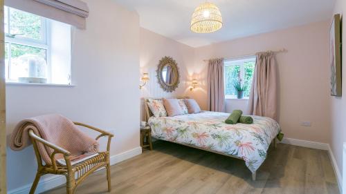 a bedroom with a bed and a chair and a window at Ty Cadwgan in Aberffraw
