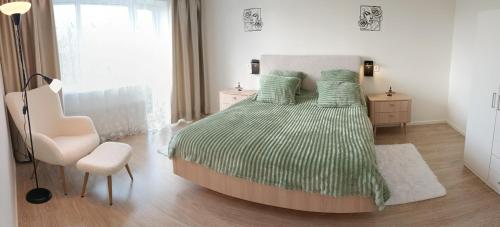 a bedroom with a bed with a green comforter and a chair at Uueka Külaliskorter in Kuressaare