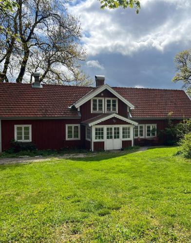 a red house with a red roof and a green yard at Övra Berg in Ullared
