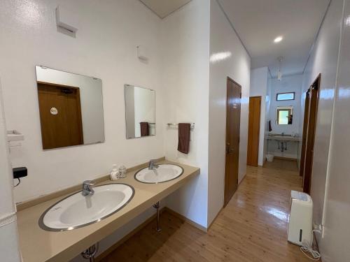 a bathroom with two sinks and two mirrors at Hostel Mosura no Tamago in Motobu