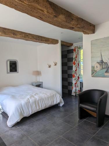 a bedroom with a white bed and a black chair at La Maison du temps retrouvé in Berville