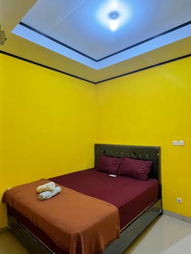a room with a bed with yellow walls at Kurniawan Homestay in Pulau Sarang