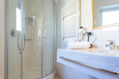 a bathroom with a glass shower and a sink at Hotel Kronplatz in Valdaora