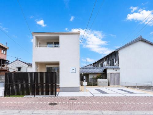 a white house with a black fence in front of it at HIRO HOUSE Marugame - 丸亀駅徒歩5分 in Marugame