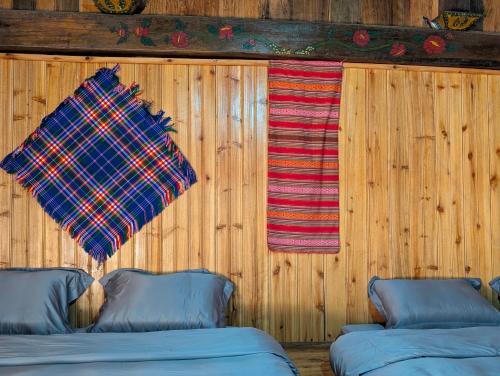 a blanket hanging on a wooden wall next to two windows at Mắn Mẩy homestay in Tả Van