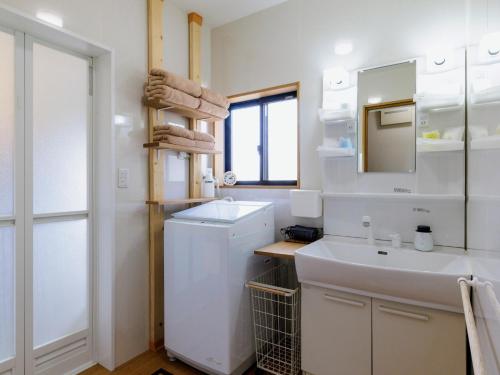 a bathroom with a sink and a washer and dryer at Holiday Home 郷 in Minami Aso
