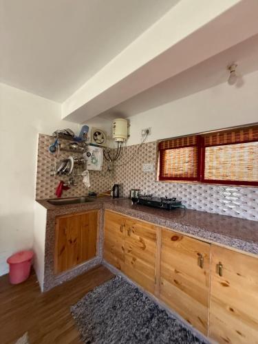 a kitchen with wooden cabinets and a counter top at Gound Floor Studio Appartment in Kulu