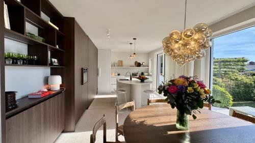 a dining room with a table with a vase of flowers at House W - North Sea Stays in De Haan