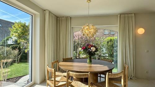 a dining room with a table with a vase of flowers at House W - North Sea Stays in De Haan