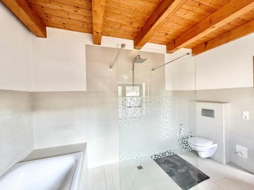a white bathroom with a shower and a toilet at Kachelofenhaus in Fehmarn