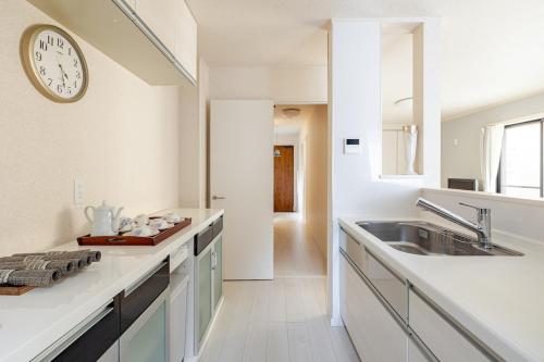 a kitchen with a sink and a clock on the wall at Sea Breeze 三浦 in Miura