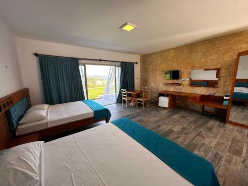 a hotel room with two beds and a desk at Golden Hill Hotel in Rizokarpaso