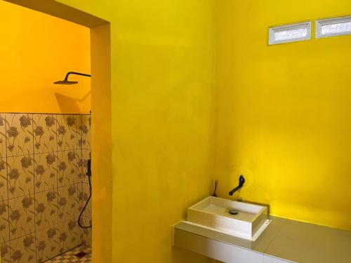 a bathroom with a yellow wall with a sink at Kurniawan Homestay in Pulau Sarang