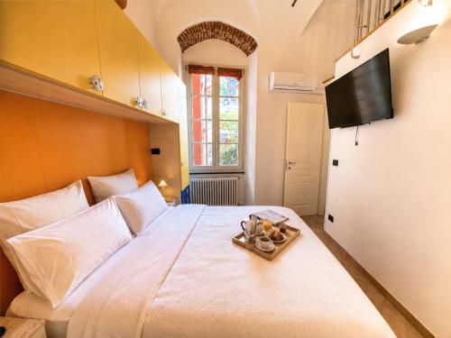 a bedroom with a large white bed with a television on the wall at Rivierarent Casa Nemo in Finale Ligure