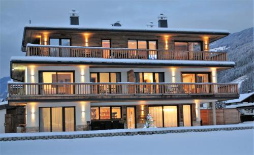 a large house with a large deck in the snow at Alpinliving.Tirol in Aschau