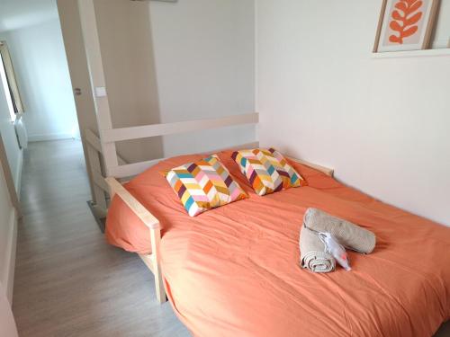 a bed with an orange blanket and two pillows at L'ESPOIRENTHESE T2 35m2 in Nieuil-lʼEspoir