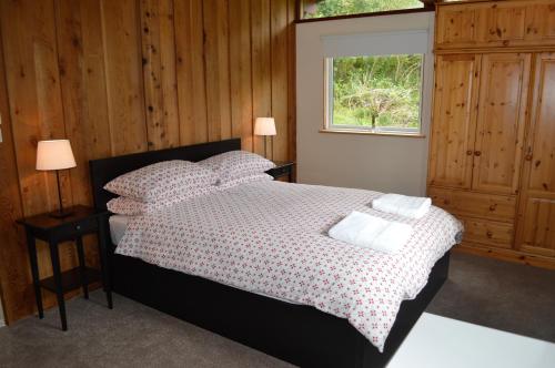 ein Schlafzimmer mit einem Bett mit Kissen und einem Fenster in der Unterkunft Cockleshell Lodge in Otter Ferry