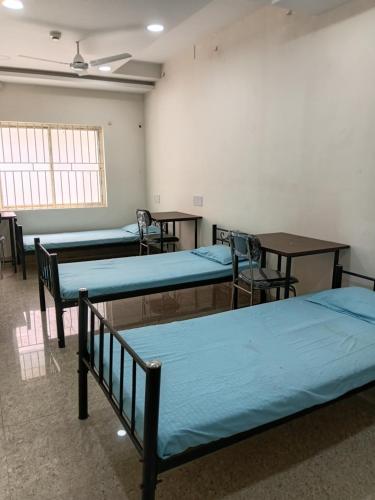 a room with three beds and tables and chairs at Nasa Hostel in Panchanai