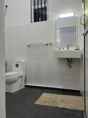 a bathroom with a sink and a toilet and a mirror at Cactus Piliyandala in Piliyandala