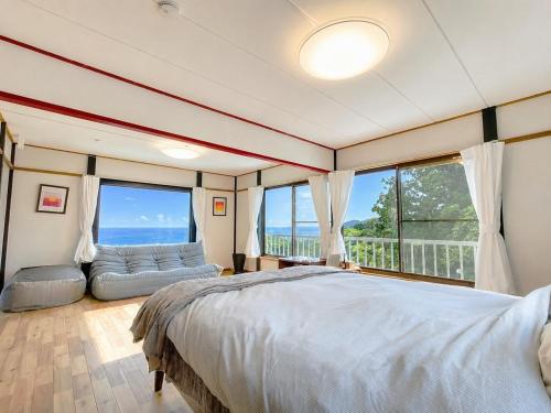 a bedroom with a bed and a couch and windows at Natuur one Kamogawa in Minamiboso