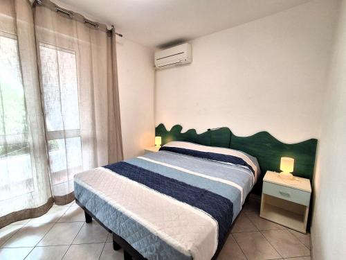 a bedroom with a bed with a green headboard and a window at Attico Resplendor Fronte mare in Rosolina Mare