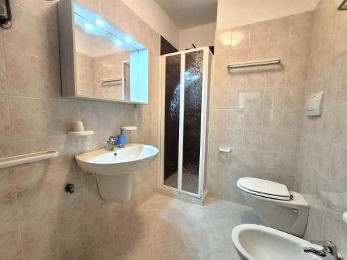 a bathroom with a sink and a toilet and a mirror at Attico Resplendor Fronte mare in Rosolina Mare