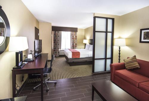 Holiday Inn Express & Suites Elkton - University Area, an IHG Hotel في إلكتون: غرفة في الفندق بها سرير وأريكة ومكتب