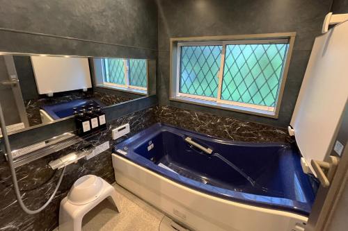 a bathroom with a blue tub and a toilet at Natuur one Kamogawa in Minamiboso