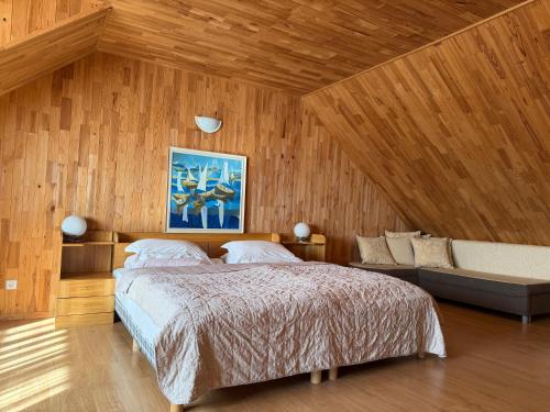 a bedroom with a large bed and a couch at Karolio Sodyba Palūšėje in Palūšė