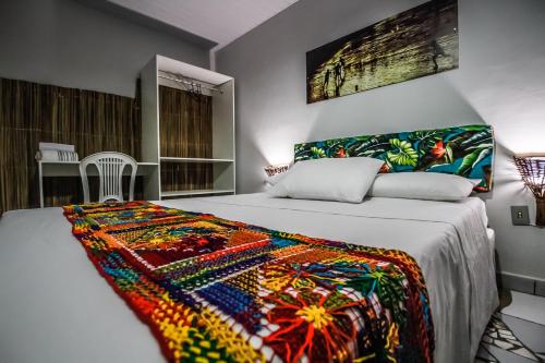 a bedroom with a bed with a colorful blanket on it at Pousada Vila Nalu in Praia do Frances