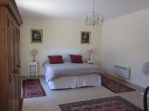 a bedroom with a bed with red pillows on it at Le Manoir Monlezun in Monlezun