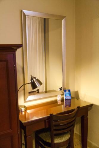 a desk with a lamp and a mirror in a room at Hotel El Almendro in Managua