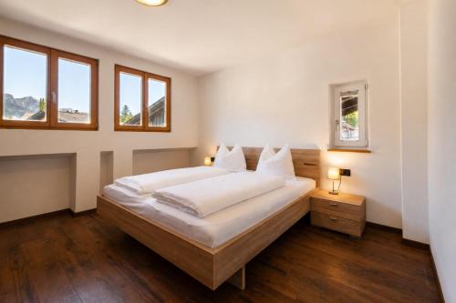 a bedroom with a large bed and two windows at Ferienwohnungen Preiss - Schenna in Schenna